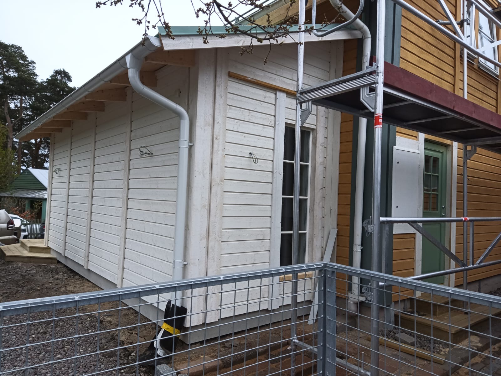 Vitt trähus med byggnadsställning under fasadrenovering